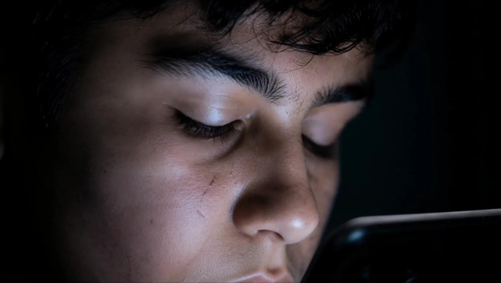 A close portrait lit by a handheld screen.