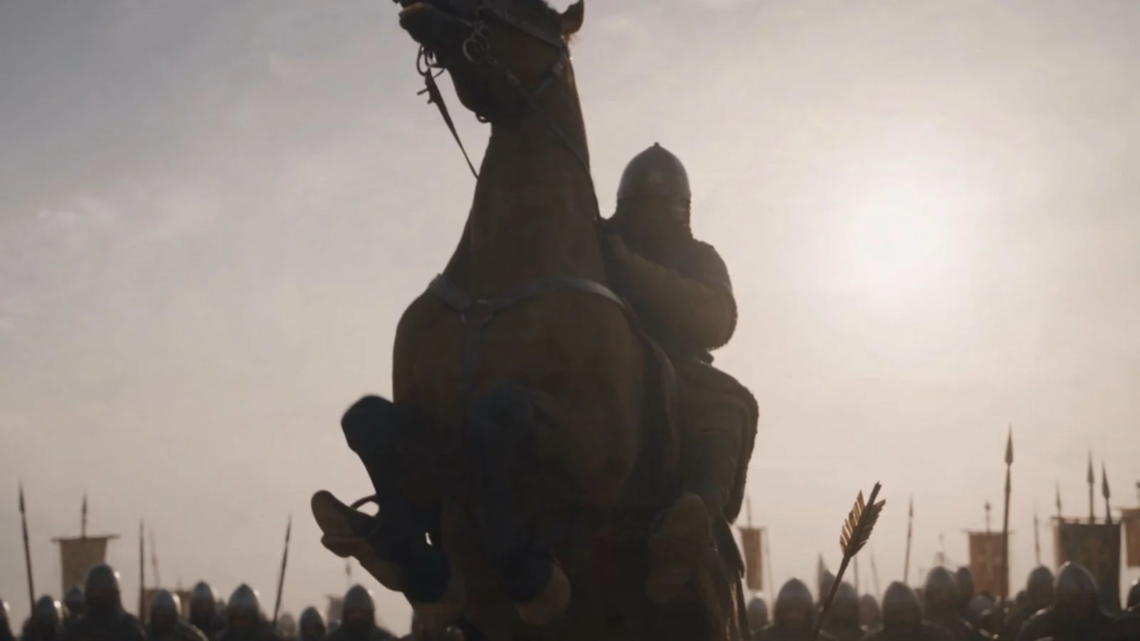 A mounted figure raising a weapon into the light.